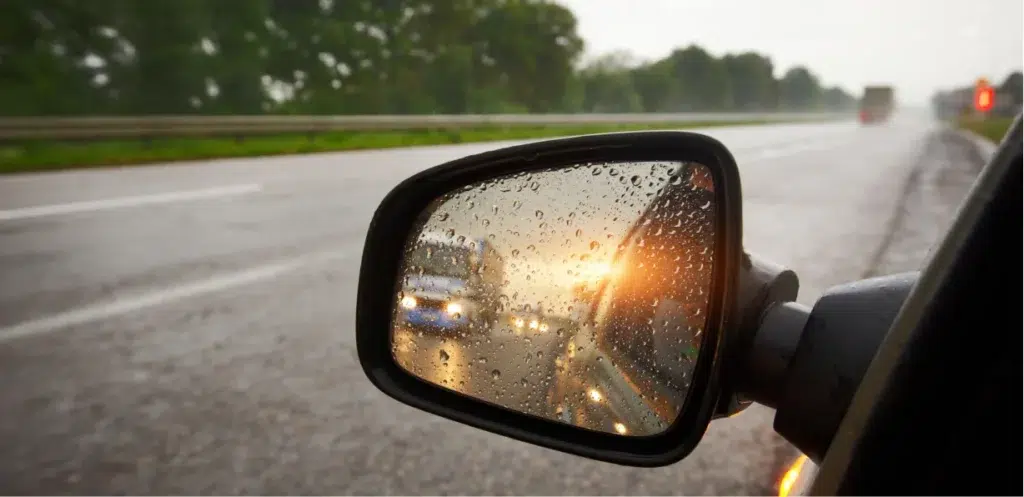 Most Dangerous Intersections for Car Accidents in Denton County wet side mirror after rain showing back of the road.