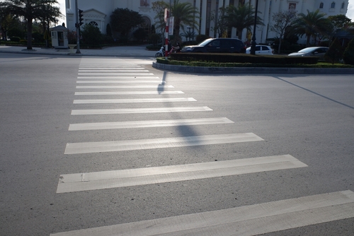 Empty pedestrian crosswalk at an intersection on a sunny day.