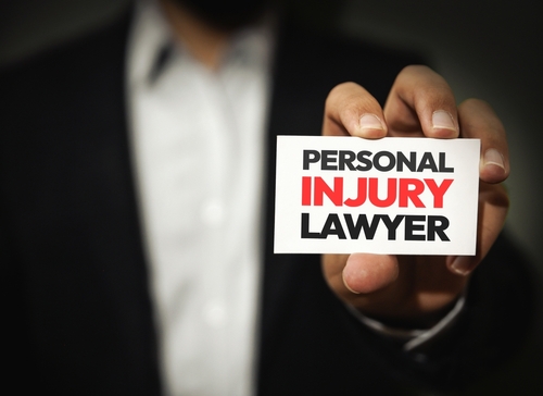 A person holding a business card that says "Personal Injury Lawyer" in bold letters.