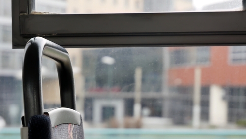 Close-up of a bus seat backrest next to a window with an urban cityscape visible outside.