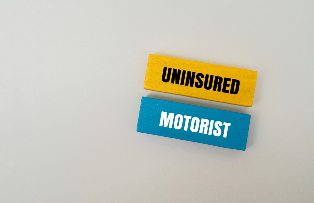 Yellow and blue wooden blocks labeled uninsured motorist concept on gray background