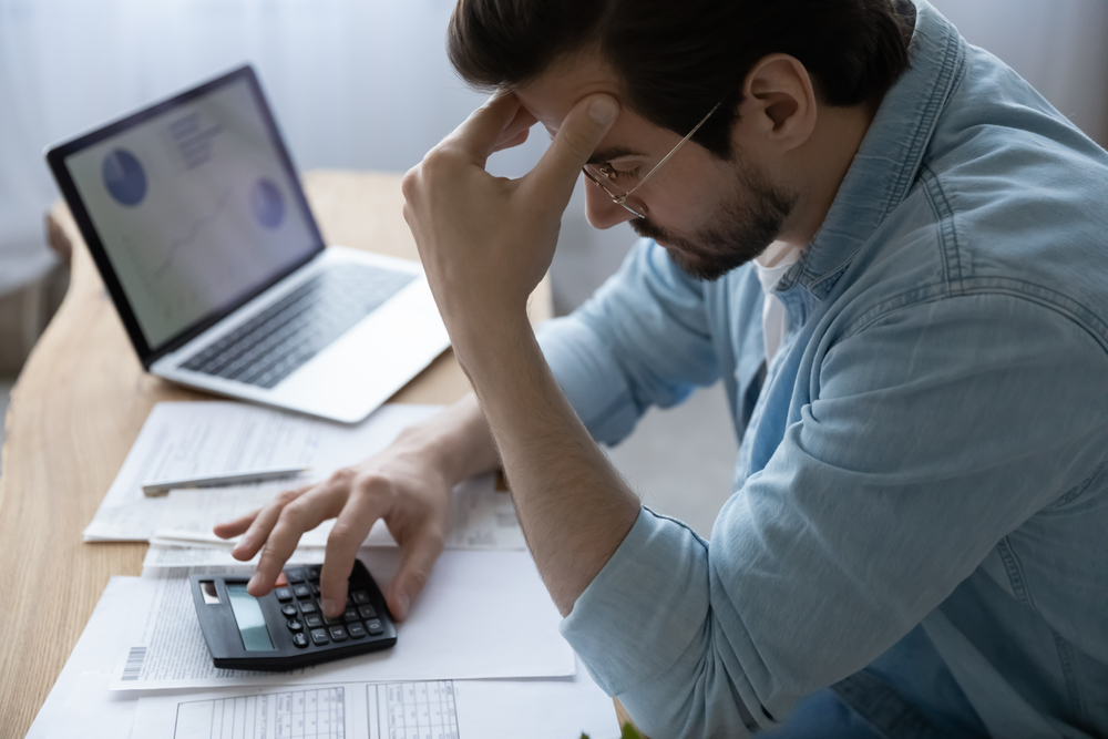 Man reviewing finances with calculator showing stress after injury impacting earning capacity with help from a Dallas traumatic brain injury lawyer
