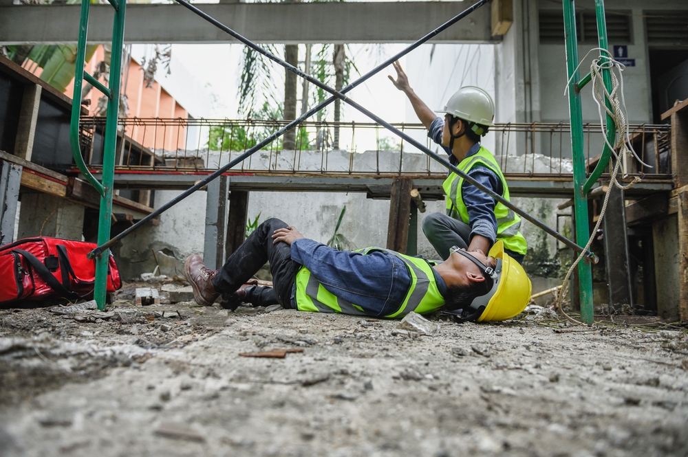 construction workers responding to a fall accident beneath scaffolding at a job site