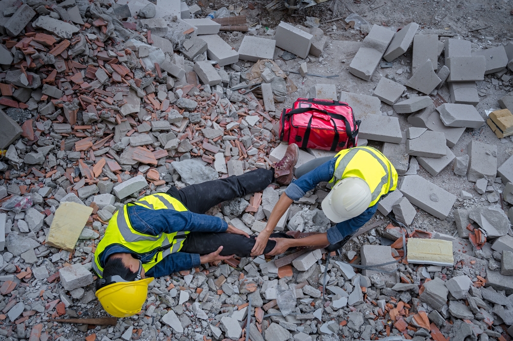 construction workers assisting injured coworker surrounded by debris at a job site accident