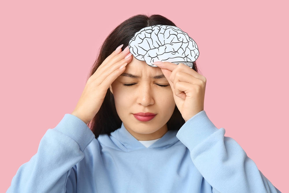 Woman holding head with illustrated brain overlay, representing traumatic brain injury symptoms